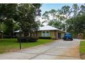 Ranch-style home features a long driveway leading to an attached garage, surrounded by green lawns and mature trees at 9365 Lemon Dr, Lake Wales, FL 33898