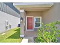 Close-up of front door entrance showing a red door, porch, and partial view of the front yard at 1417 Leamington Ln, Winter Haven, FL 33884