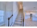 View of the staircase with carpeted steps, wood handrail, and a partial view of the open kitchen at 1417 Leamington Ln, Winter Haven, FL 33884