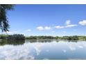 Scenic lake view featuring beautiful sky, lush green trees, and reflections on the water, offering tranquility at 4537 Fairway Oaks Dr, Mulberry, FL 33860