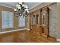 Dining area with hardwood floors, brick accent wall, large cabinet, plantation shutters, and chandelier at 6487 Ashley Dr, Lakeland, FL 33813
