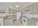 A well-lit kitchen features light green cabinets, white appliances, and tile flooring at 5879 Swallow Dr, Lakeland, FL 33809