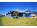 Beautifully landscaped single-story home with a blue exterior and manicured lawn on a sunny day at 5120 Villa Crest Way, Auburndale, FL 33823