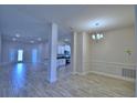 Spacious living room with wood-look tile, stylish chandelier, and an open concept design leading to the kitchen at 5120 Villa Crest Way, Auburndale, FL 33823