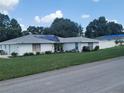 Well-kept single-story home featuring white brick, solar panels, lush lawn, and an adjacent fenced yard for privacy at 152 Audubon Ct, Winter Haven, FL 33884
