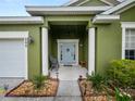 Green house exterior with light blue front door and landscaping at 808 James Way, Lake Alfred, FL 33850