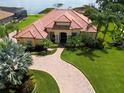 Expansive lakefront home with terracotta roof, lush lawn, and brick drive offers waterfront living at 341 Hamilton Shores Dr. Ne, Winter Haven, FL 33881