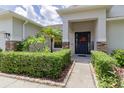 Charming home entrance with a welcoming front door, stone accents, and lush landscaping at 6769 Hampshire Blvd, Lakeland, FL 33813