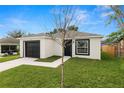 Single-story home with black garage door and front door complemented by a manicured lawn at 1918 Dr Martin L King Jr Way, Haines City, FL 33844