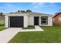 Single-story home featuring a black garage door and front door surrounded by a manicured lawn at 1918 Dr Martin L King Jr Way, Haines City, FL 33844