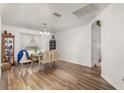 Bright dining room with wood floors, white walls, and a chandelier. Table and chairs fill the space at 215 Captain Hook Way, Davenport, FL 33837
