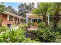 Relaxing backyard patio with pergola, pond, lush landscaping, and seating area at 7525 Catherine Dr, Lakeland, FL 33810