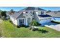 Two-story house with a two-car garage, palm trees, and a neatly landscaped lawn at 206 Clovis Pass, Winter Haven, FL 33880