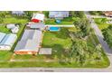 Aerial view of a spacious backyard with a swimming pool, fire pit, sheds, and lush greenery at 4390 Sunnyside Dr, Lakeland, FL 33810
