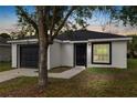 Charming single-story home featuring a black garage door and door, complemented by a well-manicured front yard and landscaping at 1217 Avenue J, Haines City, FL 33844