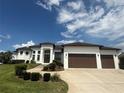 Beautiful single-story home featuring manicured lawn, an arched entryway, and a three-car garage at 5074 Shore Side Dr, Lakeland, FL 33812
