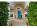 Charming home featuring a lovely archway entryway, bright blue door, and manicured landscaping at 5009 Hanover Ln, Lakeland, FL 33813
