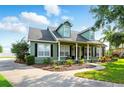 Two-story home with black shutters and dormer windows, featuring a welcoming front porch and a spacious driveway at 1935 Austin Ter, Winter Haven, FL 33884