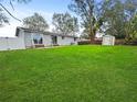 Expansive backyard with lush green lawn, white fence, storage shed, and sliding glass doors to the home at 5225 Golden Gate Blvd, Polk City, FL 33868