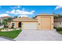 Single-story home featuring a three-car garage, paver driveway, manicured lawn, and bright exterior paint at 3802 Litchfield Loop, Lake Wales, FL 33859