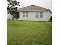 An exterior view of the house and backyard featuring a green lawn, windows, and back porch at 3136 Country Club Cir, Winter Haven, FL 33881