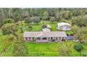 Aerial view of a brick home, with a pond and large outbuilding, nestled on a spacious lot at 9240 Moore Rd, Lakeland, FL 33809