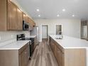 Modern kitchen featuring stainless steel appliances, wooden cabinetry, and a large island with white countertops at 723 Bentley North Loop, Auburndale, FL 33823