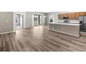 Spacious open-concept living area featuring modern kitchen with stainless steel appliances and wood laminate flooring at 723 Bentley North Loop, Auburndale, FL 33823