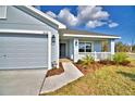 Close-up of the light-blue home's front exterior, featuring the front door and a two-car garage at 4036 Tullamore Ln, Auburndale, FL 33823