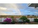 Expansive backyard with a white picket fence and colorful flowers under a vibrant rainbow at 1155 Towergate Cir, Lake Wales, FL 33853