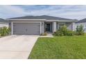 One-story home with gray exterior, attached garage, and landscaped front yard at 1225 Third Ct, Eagle Lake, FL 33839