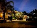 A lovely home and entryway illuminated at dusk with mature trees at 535 Narrow Pond Rd, Polk City, FL 33868