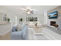 Bright living room boasts a ceiling fan, comfortable seating, and fireplace with scenic television above mantel at 6029 Avocado Dr, Indian Lake Estates, FL 33855