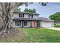 Charming two-story home featuring a well-manicured lawn, light gray paint, brick accents, and a driveway leading to a two-car garage at 1305 Avenue S Nw, Winter Haven, FL 33881