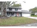 Two-story house with gray painted brick and a large tree in the front yard at 1305 Avenue S Nw, Winter Haven, FL 33881