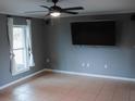 Living room with tile floors, ceiling fan, and large TV at 1305 Avenue S Nw, Winter Haven, FL 33881