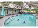 Enclosed pool area with in-ground pool with dolphin tiles, hot tub, waterfall, and screen enclosure with covered seating at 1305 Avenue S Nw, Winter Haven, FL 33881