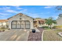 Tan one-story house with a two-car garage and landscaped yard at 6069 Kittiwake Dr, Lakeland, FL 33809