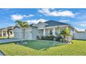 Newly built home with two-car garage, landscaping, and palm trees at 241 Walkers Point Dr, Auburndale, FL 33823