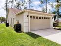 Tan house with two-car garage, landscaping, and large trees at 8052 Sugar Pine Blvd, Lakeland, FL 33810