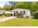 Front view of a white single-wide manufactured home with carport and landscaping at 32334 Oak Park Dr, Leesburg, FL 34748