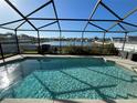 Inviting screened-in pool area with lush landscaping and a serene view of the adjacent lake and neighborhood at 4018 Sundance Place Loop, Mulberry, FL 33860