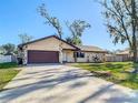 One-story house with brown garage door and stone accents, surrounded by trees at 7801 Rolling Grove W Dr, Lakeland, FL 33810