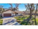 Single-story house with brown garage door, stone accents, and large yard at 7801 Rolling Grove W Dr, Lakeland, FL 33810