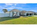 Well-maintained single-story home featuring an expansive green lawn, lush landscaping, and attached two car garage at 1570 Doves View Cir, Auburndale, FL 33823