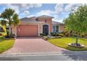 Exterior view of a charming one-story home with a brick driveway and well-manicured lawn at 453 Treviso Dr, Kissimmee, FL 34759