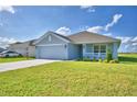 Single-story house with light blue exterior, two-car garage, and landscaped yard at 1214 Tagliamento Ln, Haines City, FL 33844