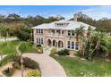 Elegant tan two-story home featuring a metal roof, arched windows, a front balcony, and a brick-paved driveway at 1665 Blue Heron Ln, Lakeland, FL 33813