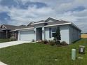 Single-story home with light blue exterior paint, two-car garage and a well manicured lawn at 237 Piave St, Haines City, FL 33844