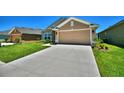 Tan house with a two-car garage and neatly landscaped front yard at 527 Tanaro Ln, Haines City, FL 33844